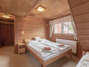 A wooden cabin bedroom with a single bed, a nightstand, a window with curtains, and a radiator. - U Dvou vleků by Interhome (Pec pod Snezkou)