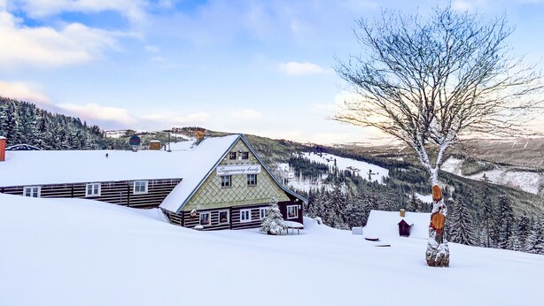 Un chalet enneigé, doté d’un toit triangulaire et d’une enseigne indiquant « Sopranen Lodge ».