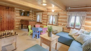 L’intérieur d’un chalet confortable, avec une cheminée, un canapé, des fauteuils colorés, une table basse et une table de baby-foot.