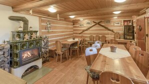 L’intérieur d’un chalet en bois, avec une cheminée en pierre, une table à manger en bois et des chaises.
