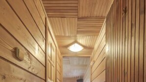 Un couloir en bois, doté d’un plancher recouvert de moquette et d’un luminaire au plafond.