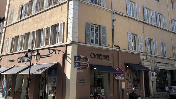A multi-story building with storefronts on the ground floor, including a pharmacy and a boutique. - Appartement Centre de Trévoux (Trévoux)
