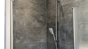 A shower with a handheld showerhead and a wall-mounted rain showerhead in a tiled room. - Appartement Centre de Trévoux (Trévoux)