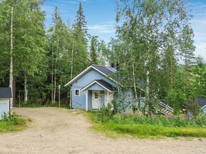 Une petite maison à un seul étage, dotée d’un toit à pignon et entourée d’une forêt dense.