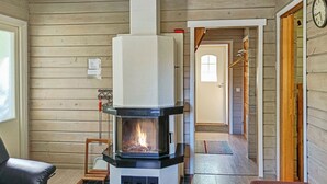 Tunnelmallinen huone, jossa on puukamiina, musta nahkainen nojatuoli ja puinen penkki.