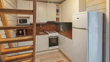 A compact kitchen with white cabinets, a microwave, a stove, and a refrigerator.