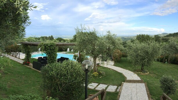 Ein Garten mit Swimmingpool, Sitzgelegenheiten im Freien und einem gepflasterten Weg.