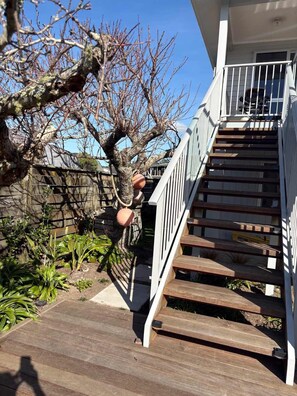 A wooden staircase leading to a white balcony with a railing. - Hosts on the Coast - Catch of the Day (Cooks Beach)