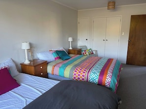 Une chambre avec deux lits, une table de chevet, une commode et une armoire.