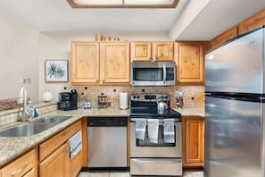 A modern kitchen with wooden cabinets, stainless steel appliances, and a tiled backsplash.