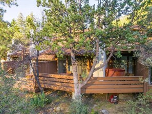 A cabin with a wooden deck, surrounded by trees.