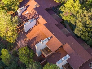 An aerial view of a property with multiple buildings, including a main structure with a flat roof and several smaller structures with gabled roofs.