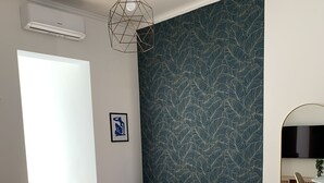 Moderni olohuone, jossa on vaaleanpunainen sohva, pyöreä valkoinen pöytä ja kuviollinen seinä.