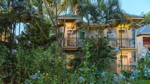 A two-story building with balconies, surrounded by dense foliage.