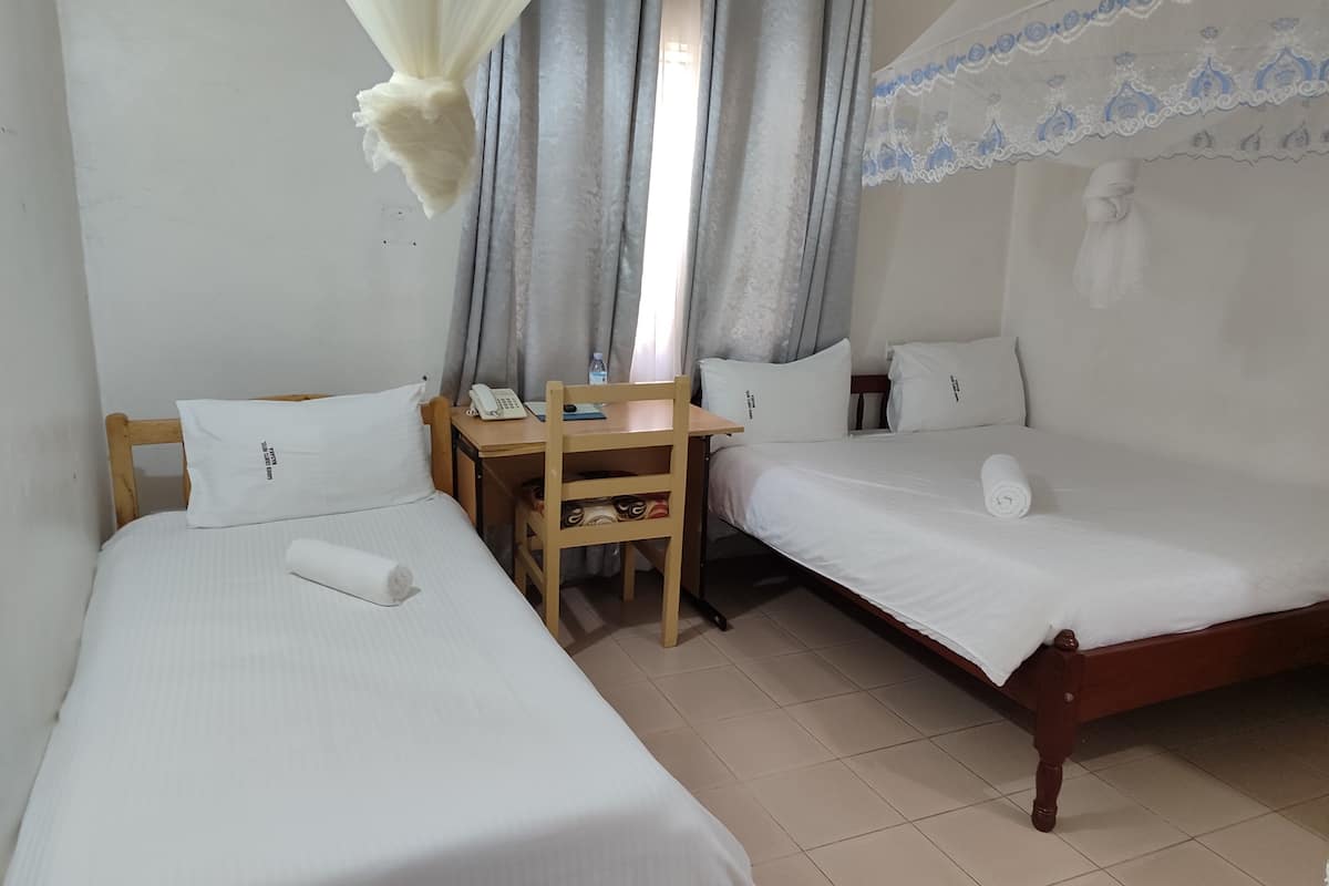 A room with two single beds, a wooden desk with a telephone, and a chair.