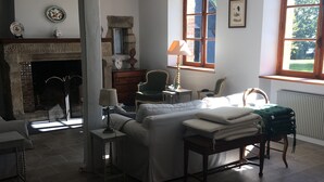 Ein geräumiger Raum mit Kamin, einem Bett, einem Sessel und einem Tisch.