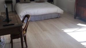 Ein Schlafzimmer mit Bett, Schreibtisch, Stuhl, Lampe und Kommode.