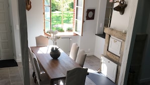 Ein Essbereich mit einem langen Holztisch, vier Stühlen und einem Blumenstrauß.