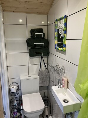 Ein kleines Badezimmer mit Fliesen, Toilette, Waschbecken und Handtuchhalter.