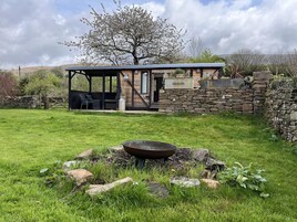 Un área de estar al aire libre de estilo rústico, con muros de piedra y una estructura cubierta.