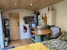 Una cocina pequeña con armarios de madera, un lavamanos y diversos utensilios colgando arriba.