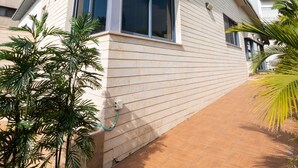 Una casa moderna de dos pisos con techo plano, ventanas grandes y una zona de patio con baldosas.