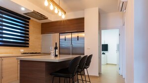 Una cocina moderna con una isla central, taburetes de bar y un horno empotrado.