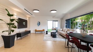 Una sala de estar moderna con un sofá, una mesa de comedor y plantas en macetas.