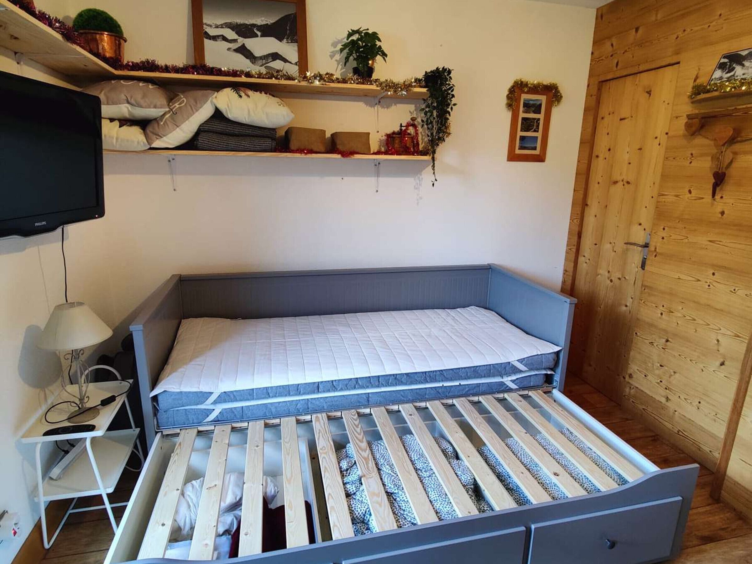 Ein gemütlicher Raum mit einem Bett, einem kleinen Tisch, einer Lampe und einem Fernseher.