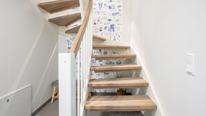 A wooden staircase with a white wall and blue illustrations. - Ferienhaus Westwind in Tönning für bis zu 4 Personen (Tönning)