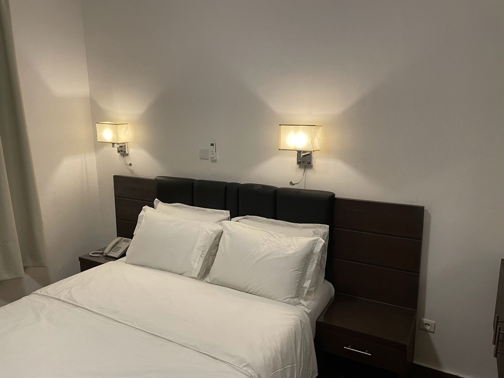 Et hotelværelse med en seng, to sengeborde og to væglamper.