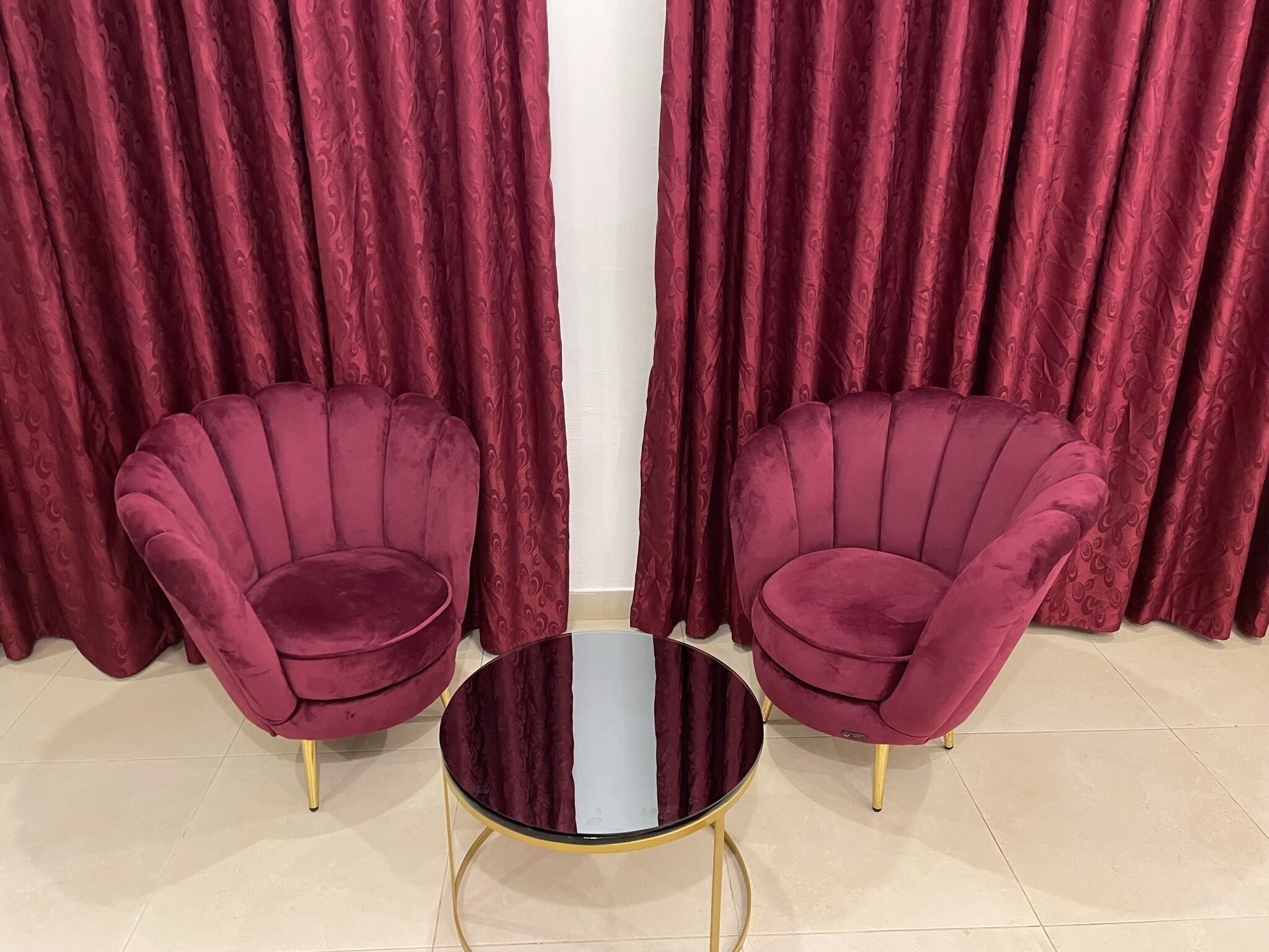 Two plush armchairs with gold legs and a round black table in front.