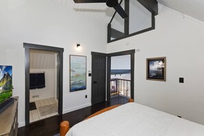 Um quarto com cama, porta para uma varanda e obras de arte nas paredes.