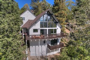 A two-story house with a balcony, surrounded by trees.