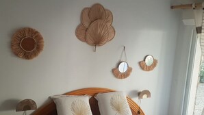 A bedroom with a wooden bed, a headboard, and wall-mounted decorative items. - Maison de Campagne, en Pleine Nature (Sari-Solenzara)