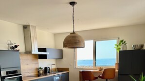 Eine moderne Küche mit Essbereich, Holzboden und Meerblick.