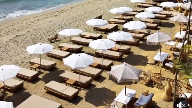 Ein Strand mit Liegestühlen und Sonnenschirmen, blauem Himmel und dem Meer.