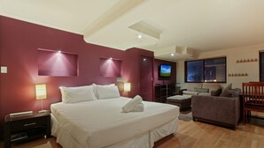 A modern hotel room with a large bed, a TV, a sofa, and a desk.