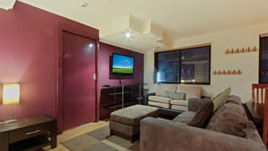 A living room with a TV, sofa, and a red door.