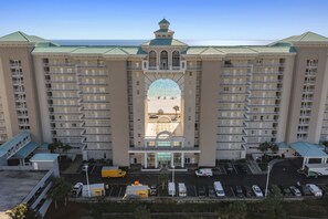 Un grand hôtel à plusieurs étages, doté d’une arche centrale et d’un parking situé à l’avant.
