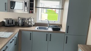 Une cuisine moderne avec des meubles gris, un four à micro-ondes en acier inoxydable, une bouilloire et un grille-pain.