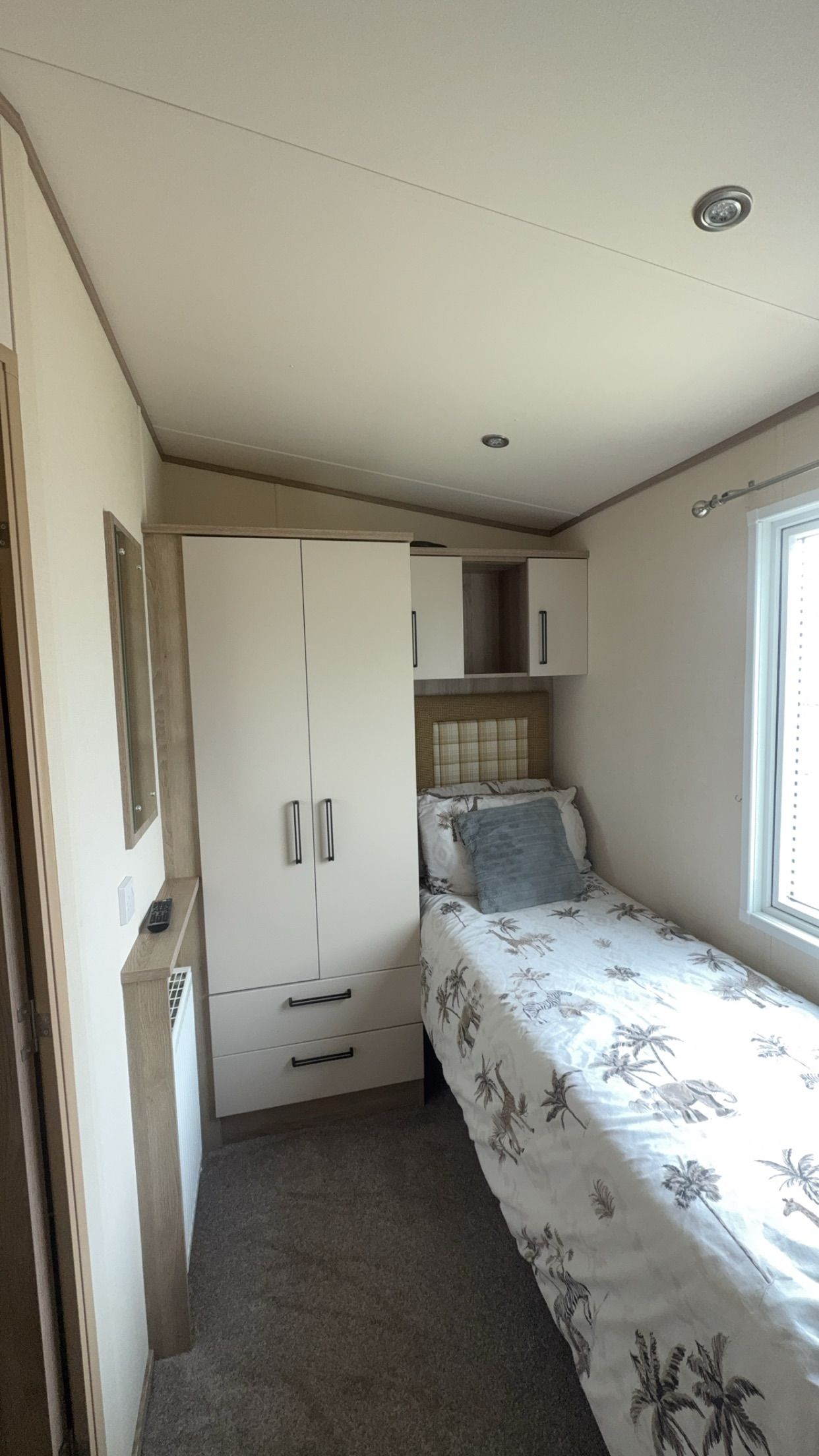 A compact bedroom with a bed, a wardrobe, and a window.