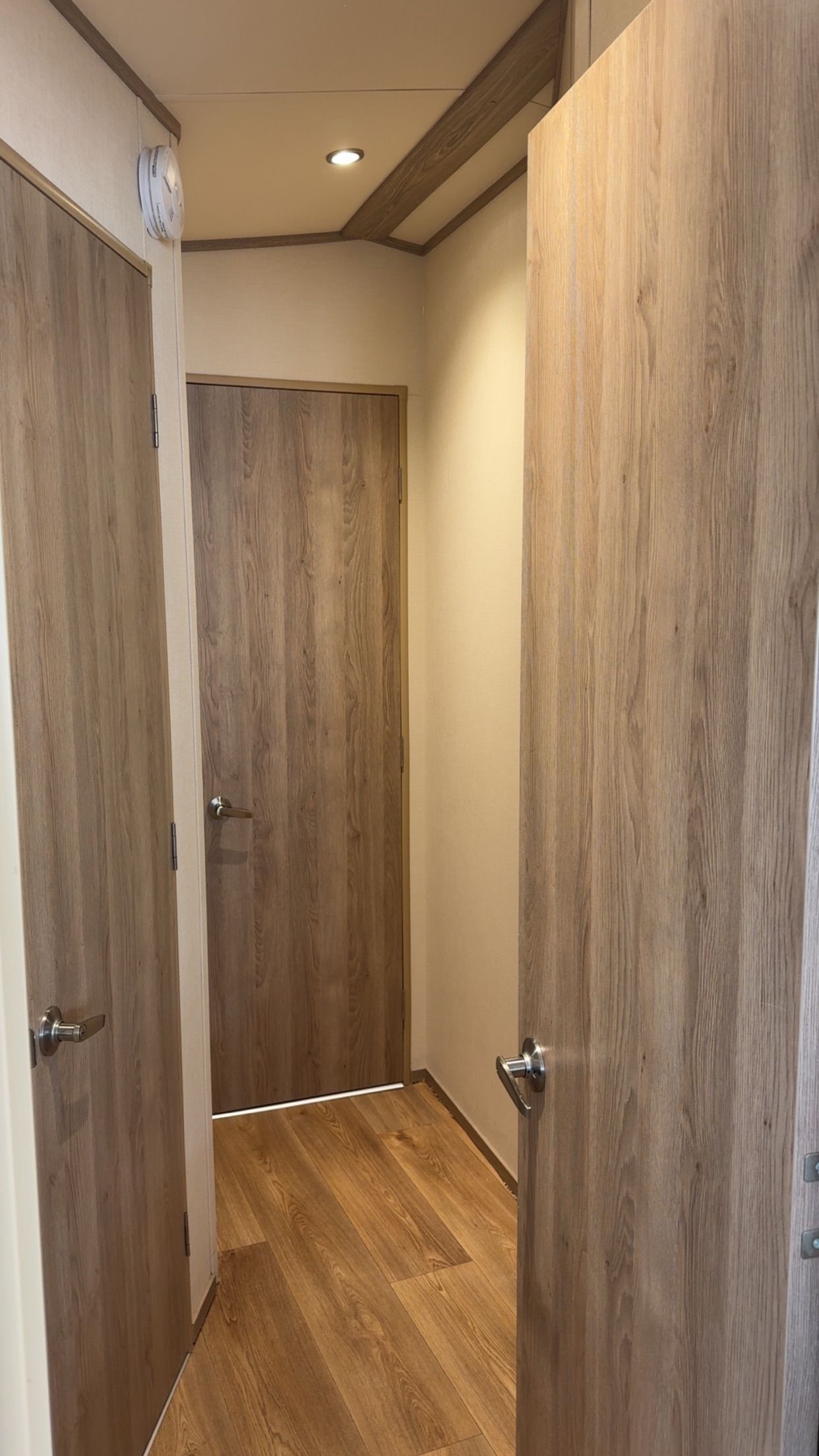 A hallway with wooden doors and a wooden floor.