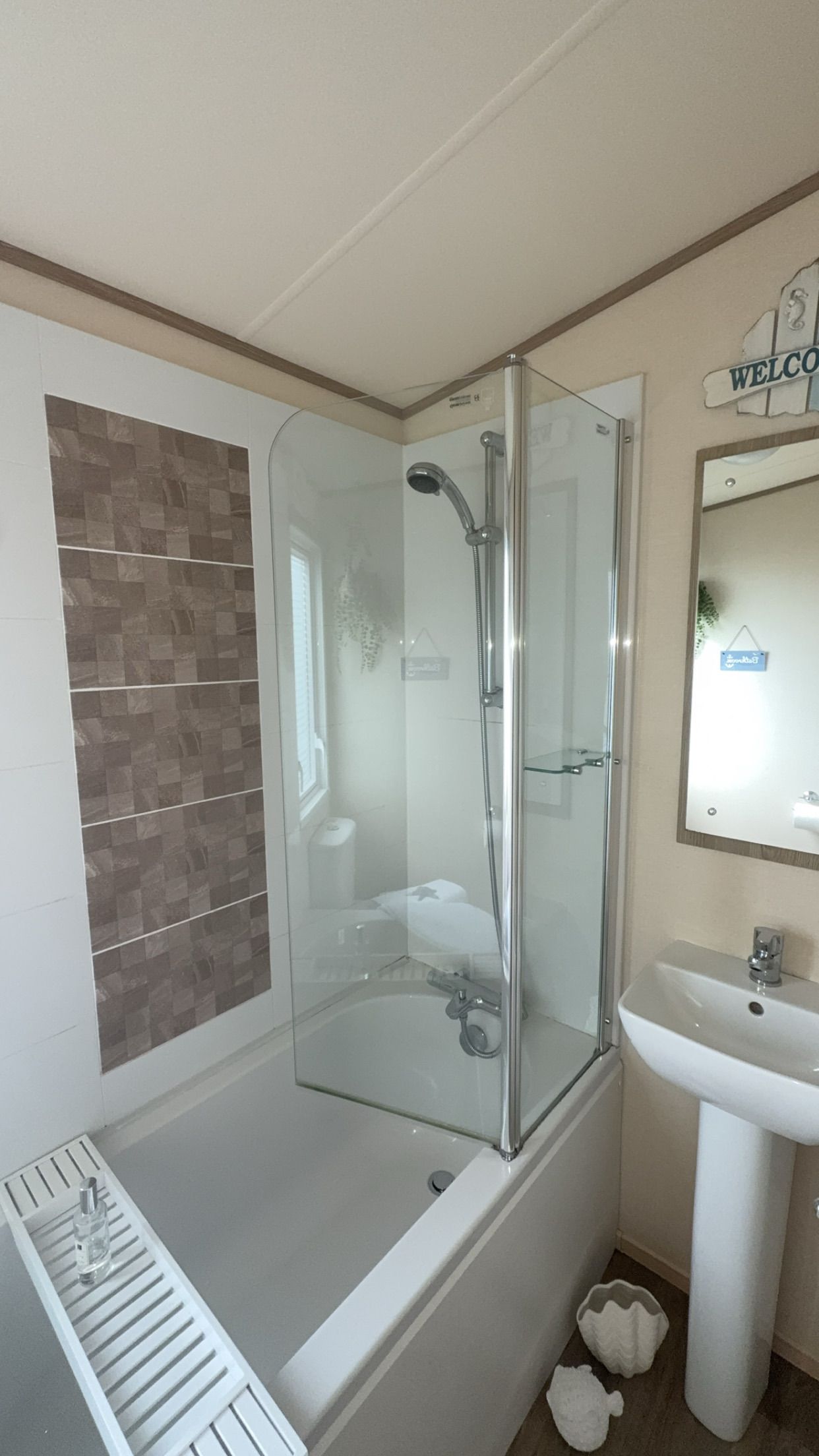 A bathroom with a glass-enclosed shower, a white sink, and a tiled wall.