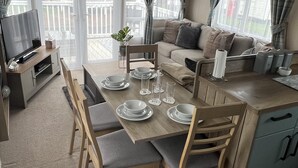 Un espace de vie compact et moderne comprenant un coin repas, un canapé et une kitchenette.