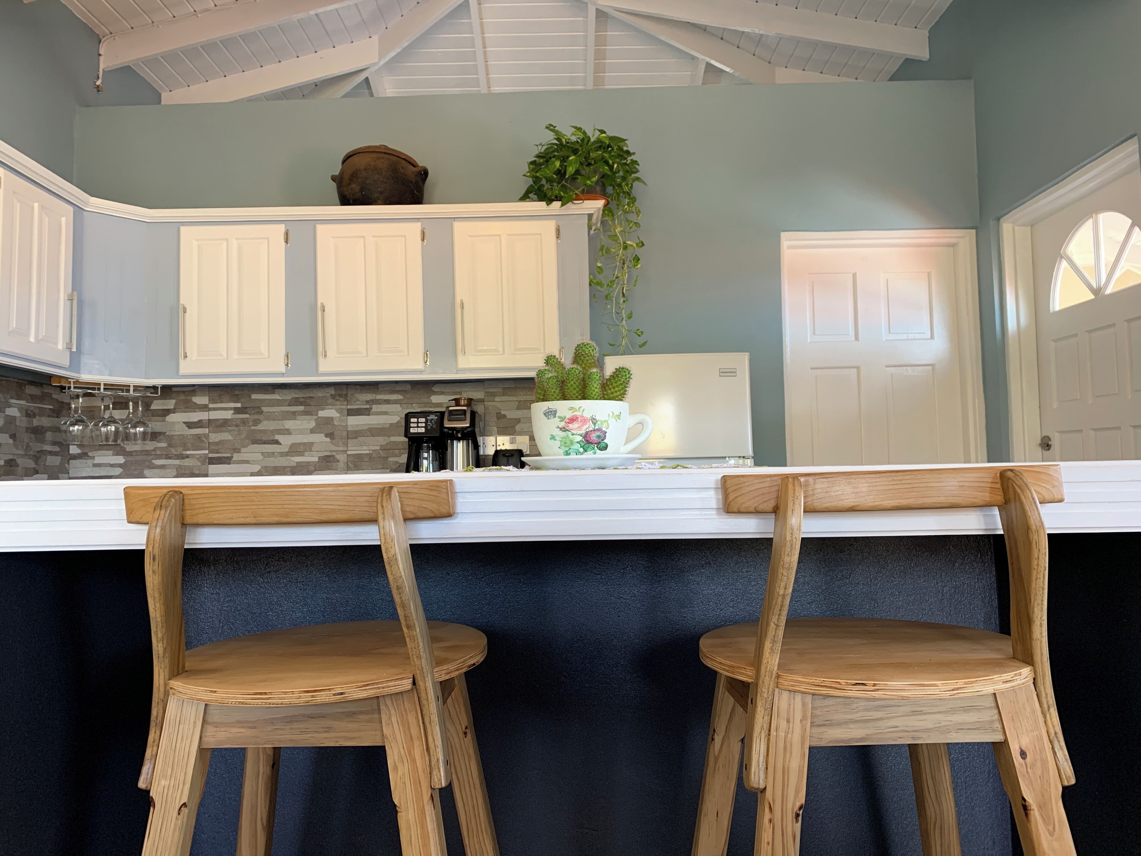 A kitchen with white cabinets, a black countertop, and two wooden bar stools.
