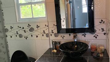 Un bagno con un lavandino nero, mobili bianchi e uno specchio sopra.