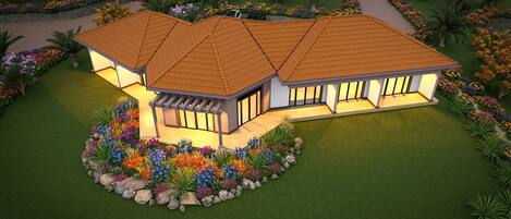 A two-story house with a tiled roof, large windows, and a landscaped garden with colorful flowers and palm trees.