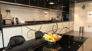 Eine moderne Küche mit schwarzer Arbeitsplatte, weißen Schränken und einer Obstschale auf dem Tisch.