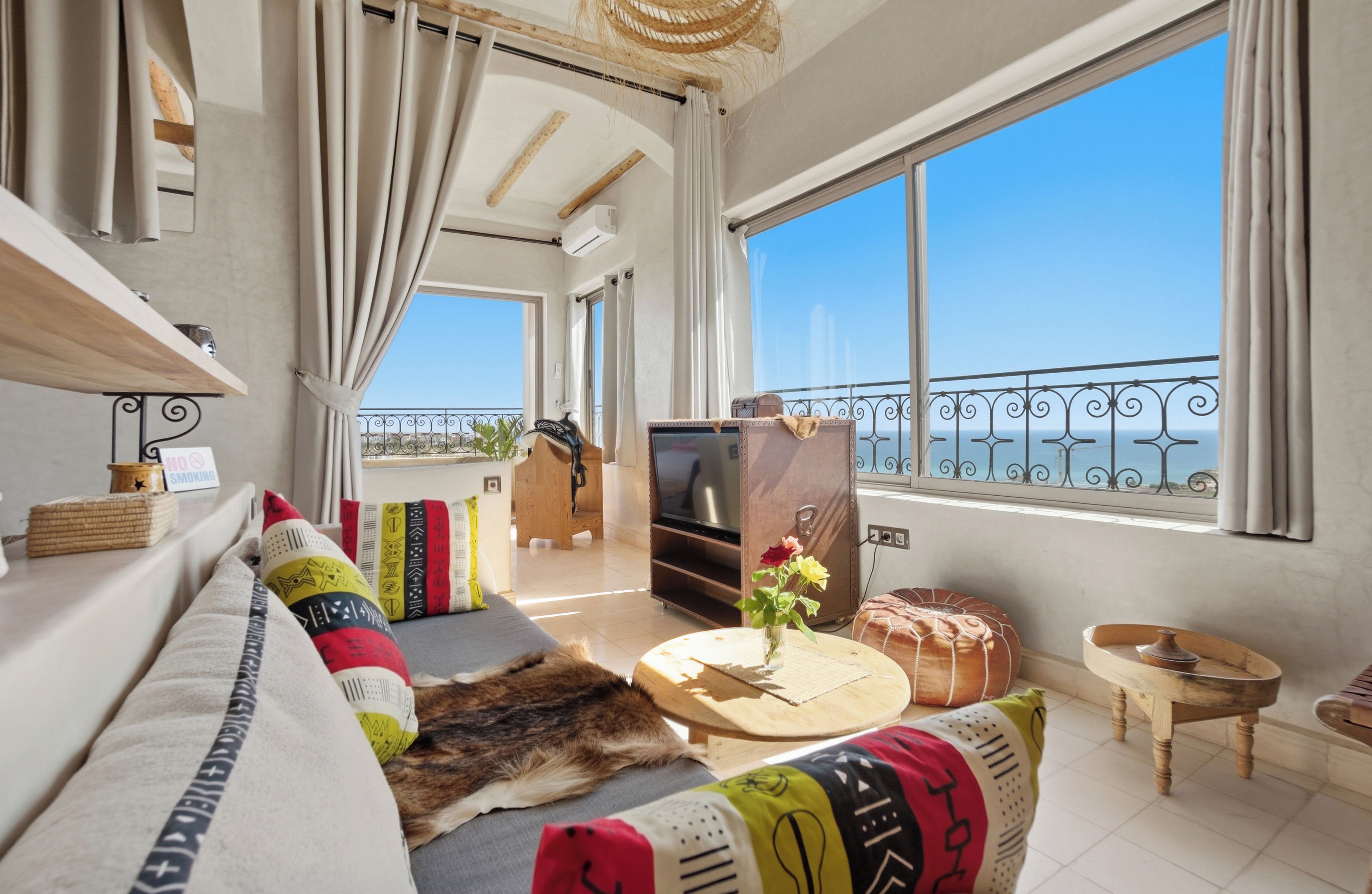 Ein modernes Wohnzimmer mit einer Couch, einem Fernseher und Blick aufs Meer.